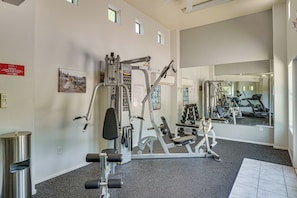 A gym with various exercise equipment, a mirror reflecting the equipment, and a sign indicating the location of the restrooms. - Pool & Hot Tub Access! Family Condo in Oro Valley (Oro Valley)