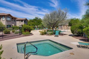 A swimming pool area with lounge chairs and a small table, surrounded by greenery and a building with a tiled roof. - Pool & Hot Tub Access! Family Condo in Oro Valley (Oro Valley)