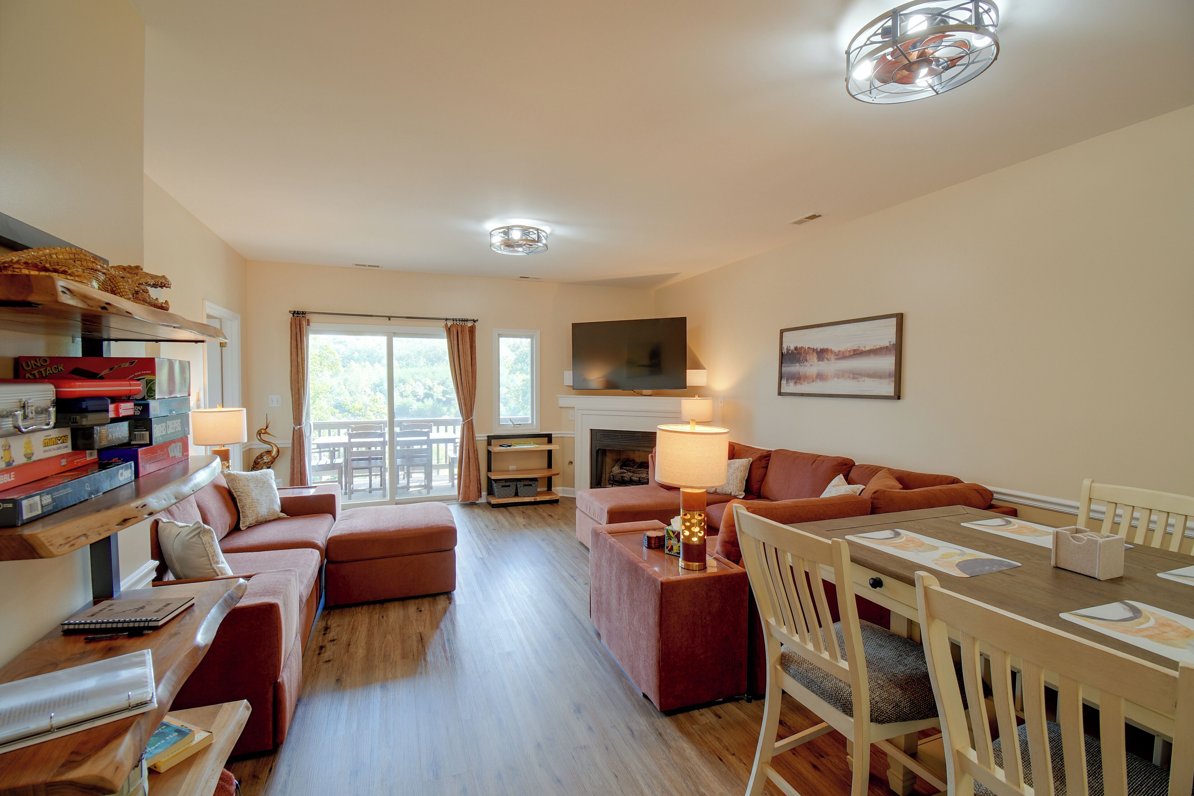 A spacious living room with a fireplace, a dining area, and a balcony with curtains.