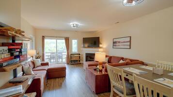 A spacious living room with a fireplace, a dining area, and a balcony with curtains.