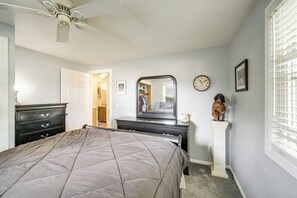 A bedroom with a bed, dresser, mirror, clock, and a decorative helmet on a pedestal. - Hot Tub, Gym & Office! Family Home in Massillon (Massillon)