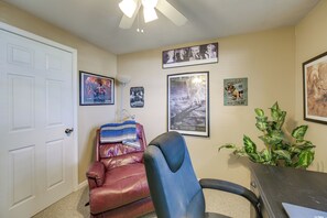 A room with a white door, a brown leather chair, a blue office chair, and a desk with a plant. - Hot Tub, Gym & Office! Family Home in Massillon (Massillon)