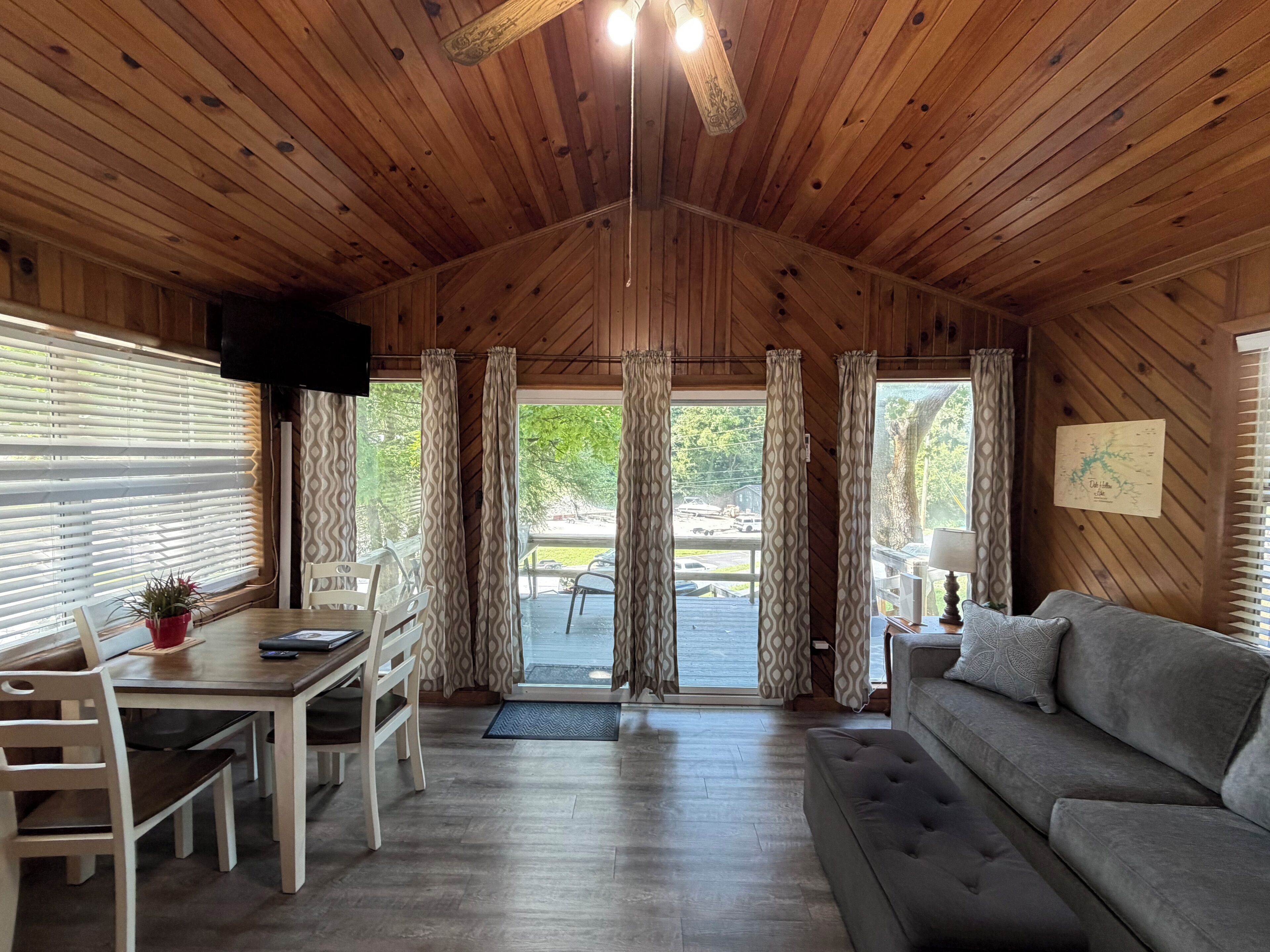A wooden interior with a dining area, sofa, and a television.
