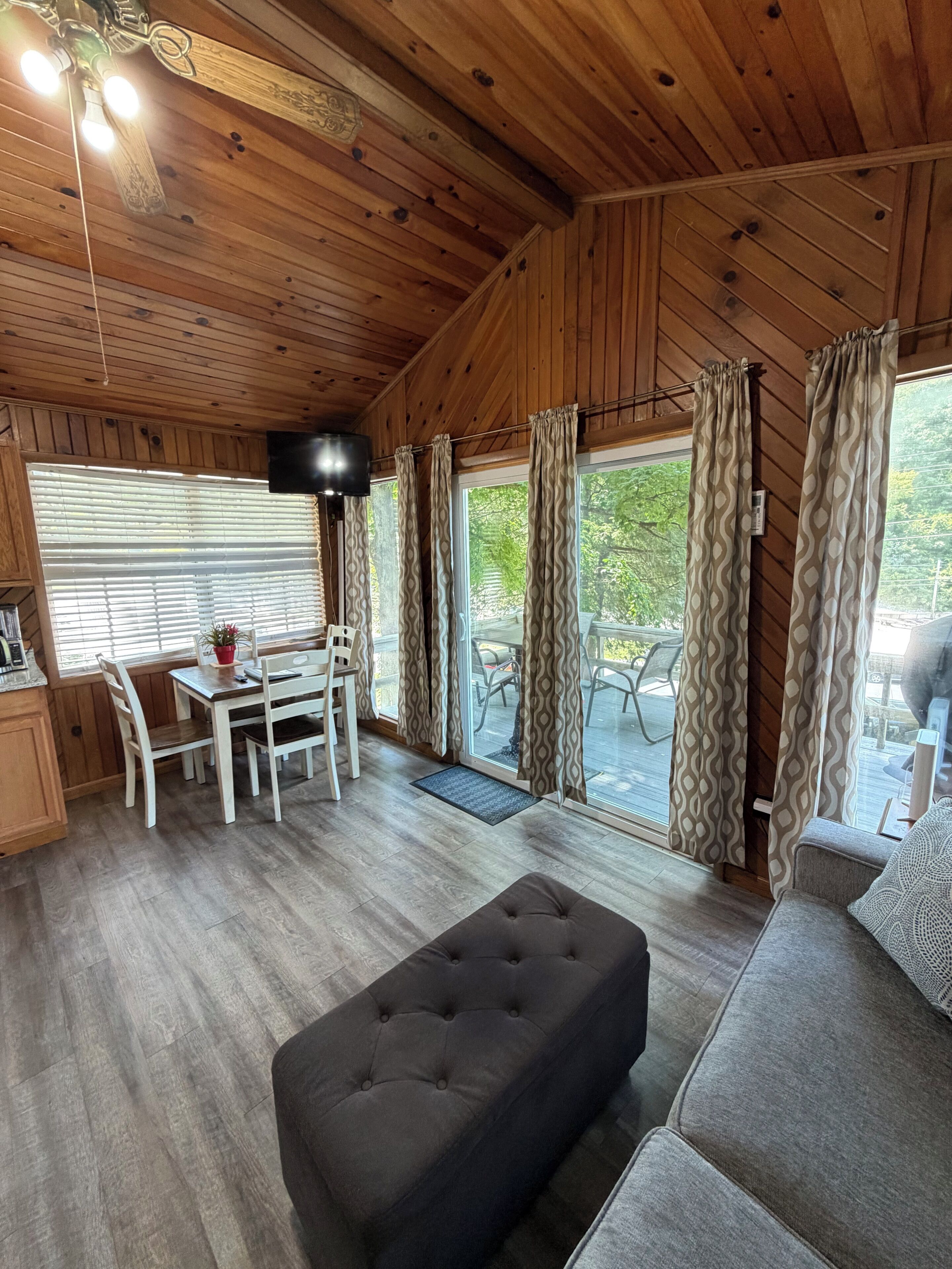 Interior de una cabaña con comedor, sofá y ventilador de techo.