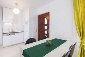 A compact kitchen with white cabinetry, a coffee maker, and a dining area with a table set for two. - Villa Olea (Čižići)