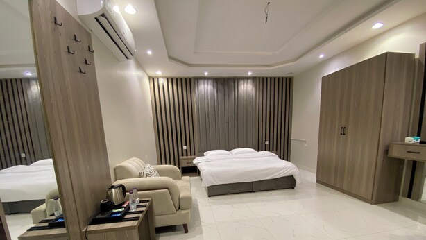 Una habitación de hotel moderna con una cama, un sofá, un escritorio con un hervidor y un armario.