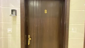 Puerta de madera cerrada con el número 8, un escalón que lleva a ella y un aplique en la pared superior.