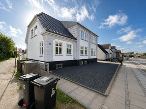 A two-story residential building with a white facade and dark roof tiles.