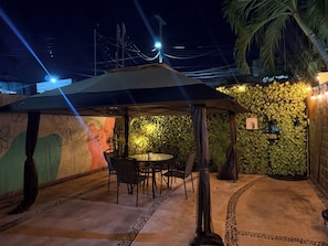 An outdoor seating area with a table and chairs, a tent overhead, and a wall covered in foliage. - Casa Villa Leo, Downtown Cancún (Cancún)