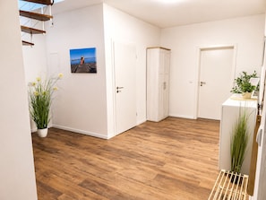 A hallway with wooden flooring, white walls, and a door with a picture on it.