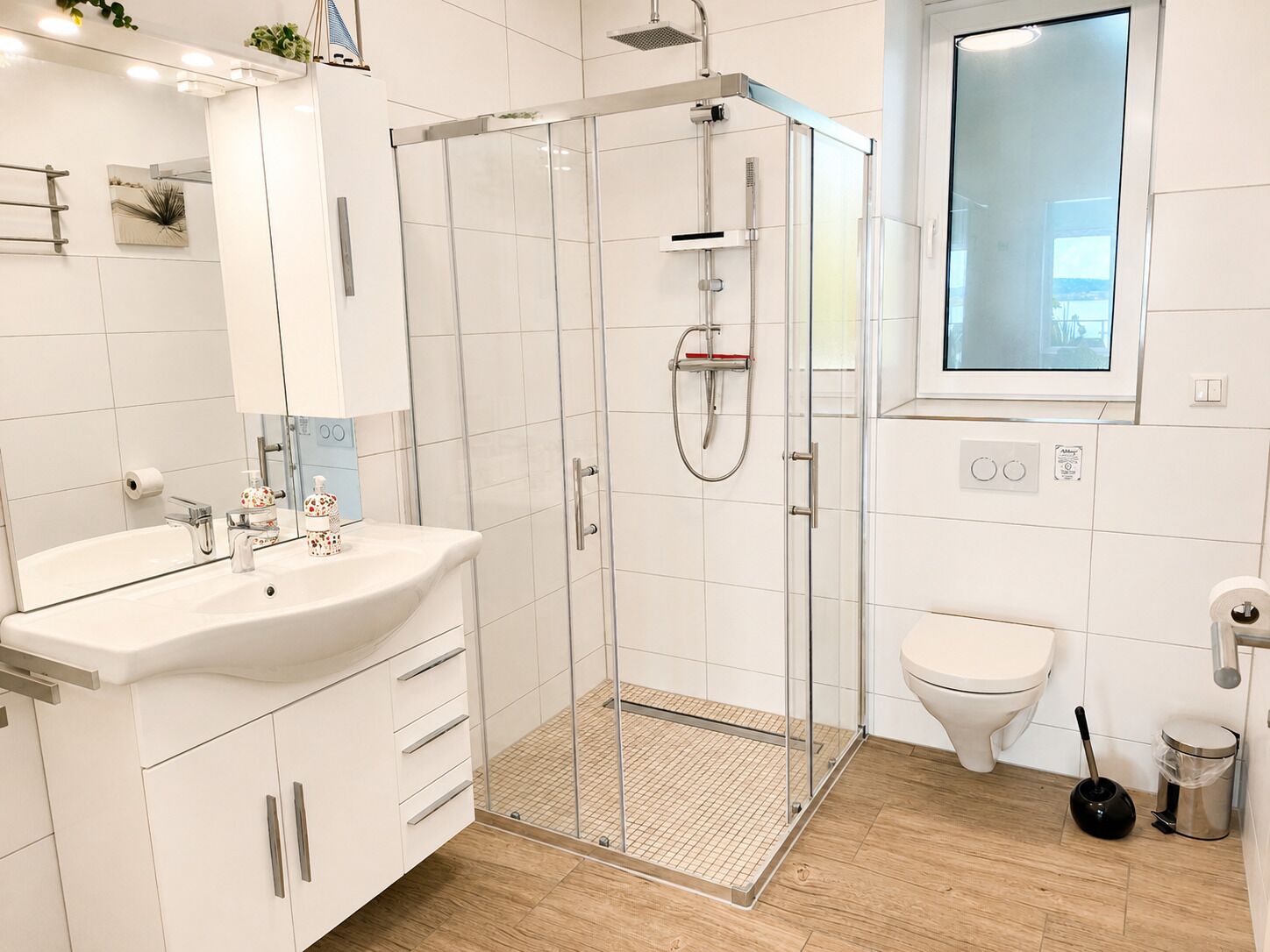A modern bathroom with a glass-enclosed shower, a sink with a mirror, and a toilet.