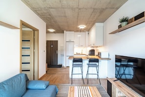 A compact living space with a kitchenette, a sofa, and a TV. - RentPlanet - Apartament Barbary (Katowice)