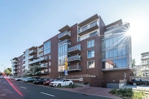 A multi-story residential building with balconies, a parking area, and a clear sky. - RentPlanet - Apartament Barbary (Katowice)