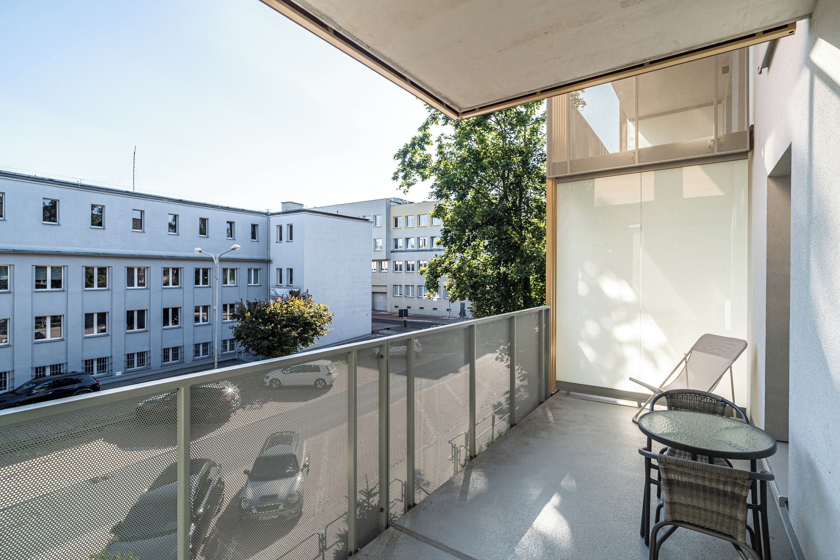 A balcony with a mesh railing, a wicker chair, and a table.