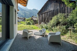 Una terrazza esterna con due sedie di plastica bianca e un piccolo tavolo rotondo, posizionata su ghiaia.