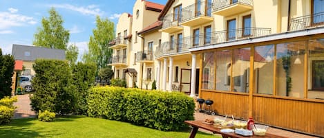 A multi-story residential building with balconies, a patio area with a barbecue grill, and a well-maintained lawn.