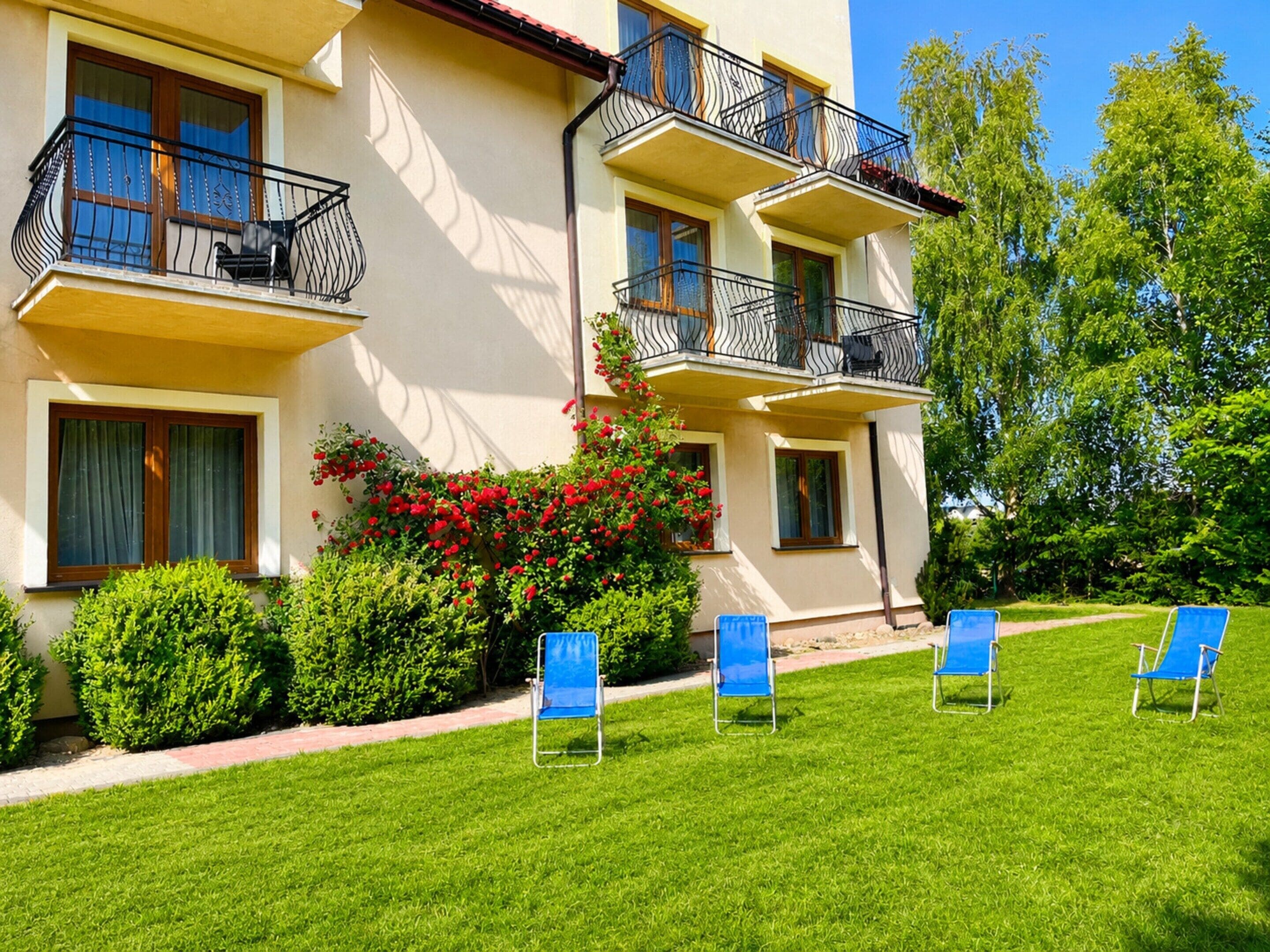 Ein Hotel mit mehreren Balkonen, einem gepflegten Rasen und Sitzgelegenheiten im Freien.