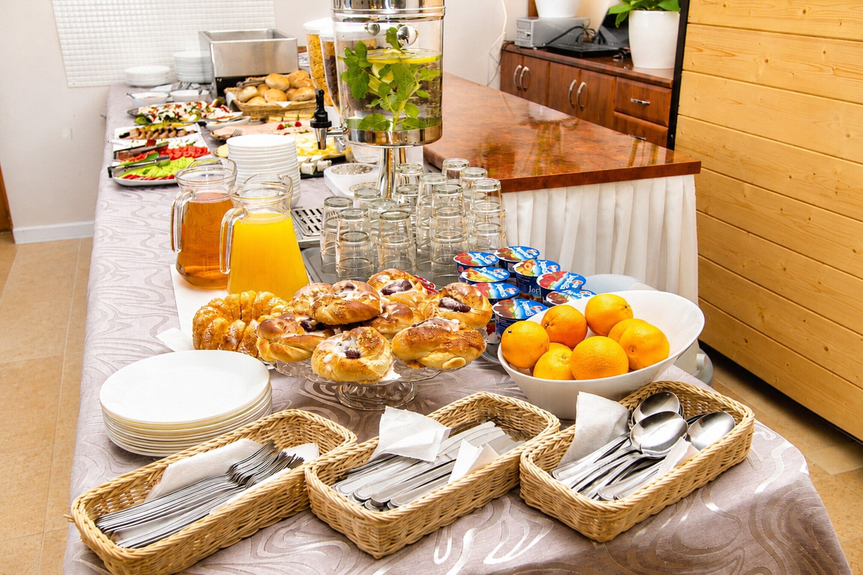 A buffet setup with various food items, including pastries, fruits, and beverages.