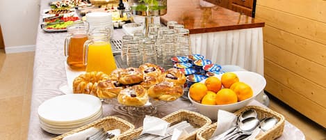 A buffet setup with various food items, including pastries, fruits, and beverages.