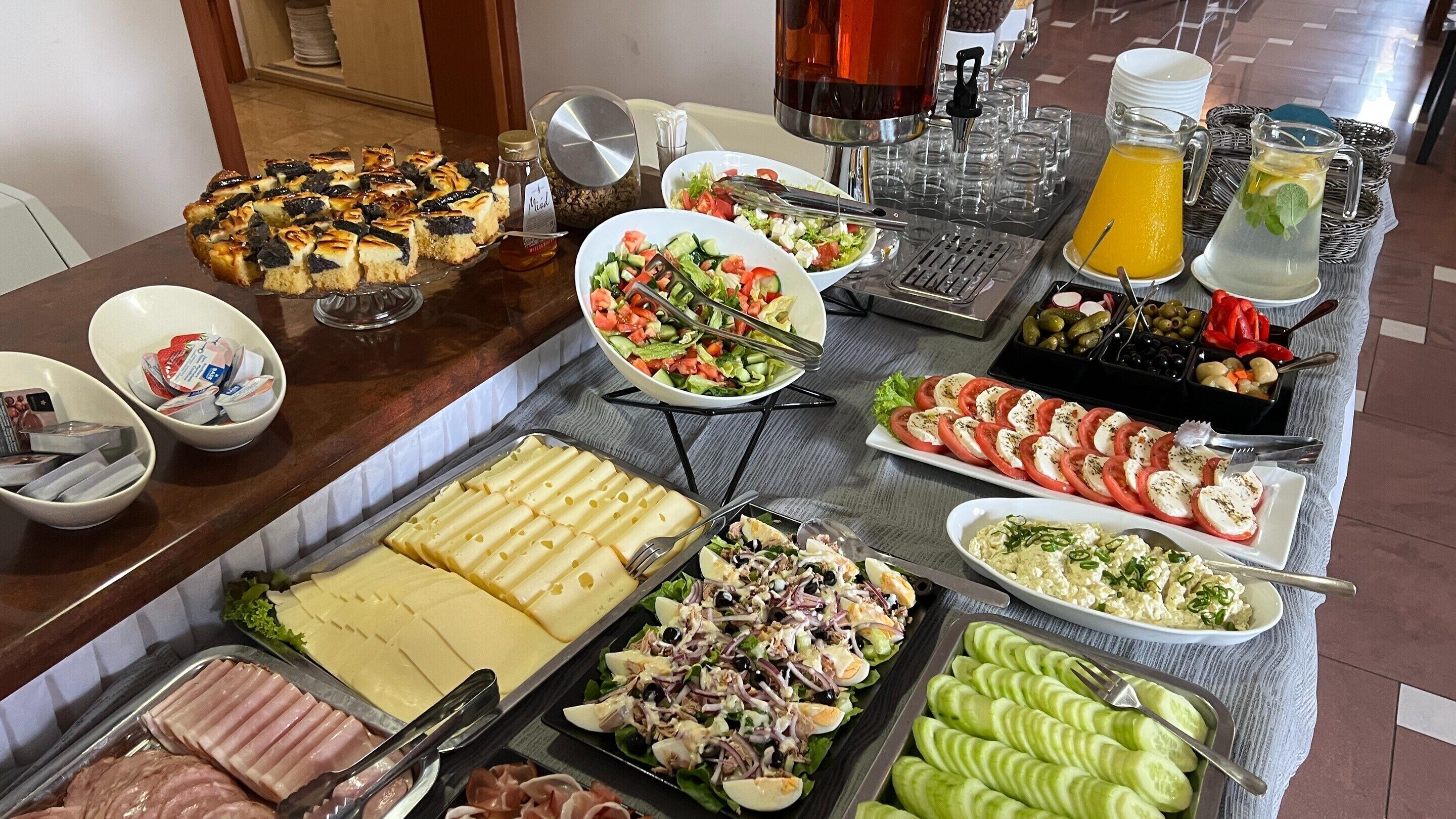 Een buffet met diverse gerechtjes, waaronder salades, kazen en vleeswaren.