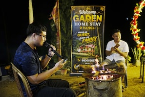 A person speaking into a microphone with a sign in the background advertising a home stay.