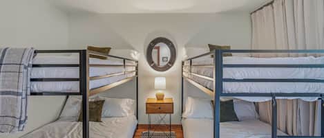 A bunk bed room with a bedside table, a mirror, and a rug.
