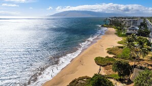 A coastal view with a beach, ocean, and a mountain in the distance. - South Maui Beach Getaway | 2BR Condo Across from Kamaole Beach II (Kihei)