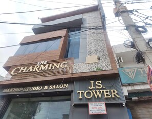 A building with signage for 'The Charming Makeup Studio & Salon' and 'J.S. Tower' with a sign indicating 'Space available for 1st floor area 2000 sqft.'