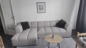 A modern living room with a sectional sofa, a round coffee table, and a framed picture on the wall.