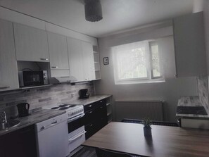 A compact kitchen with white cabinets, a microwave, a stove, and a window providing natural light.