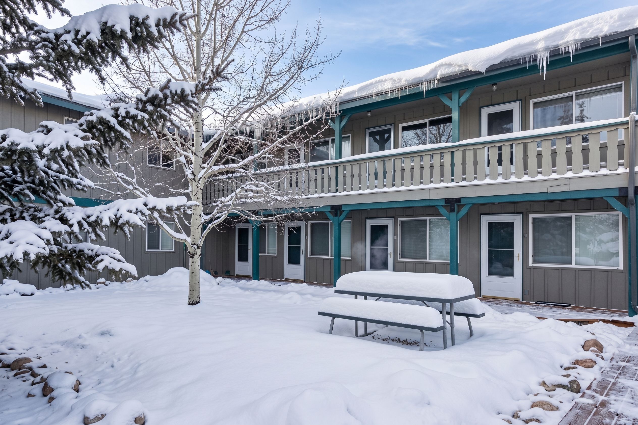 A multi-story building with a balcony and a snow-covered ground.