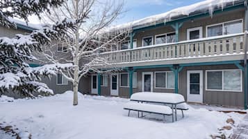 A multi-story building with a balcony and a snow-covered ground.
