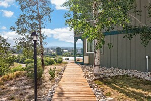 A wooden pathway leading to a building with a view of a lake and mountains.
