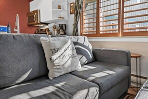 A grey sofa with a pillow that reads 'THIS IS OUR HAPPY PLACE.'