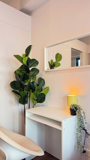 A white desk with a mirror above it, a yellow lamp, and a potted plant. - Central Makati Place With Queen bed and 55 Inch Smart TV (Makati)