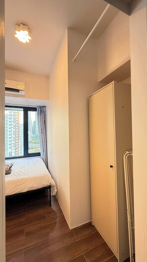 Un dormitorio con cama, ventana con cortinas, aire acondicionado y armario.