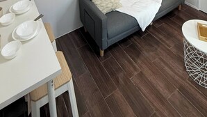 Moderni olohuone, jossa on harmaa sohva, valkoinen pöytä, jossa on lautasia, ja abstrakti taideteos seinällä.