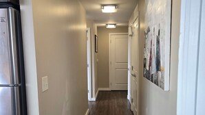 Un couloir étroit avec un plancher en bois, un tapis et un réfrigérateur sur le côté gauche.