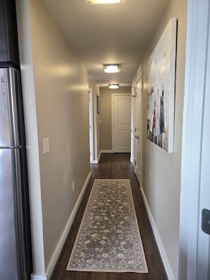 A narrow hallway with a wooden floor, a rug, and a refrigerator on the left. - Stunning Arlington Condo with Balcony & Views Near Pentagon City (Arlington)