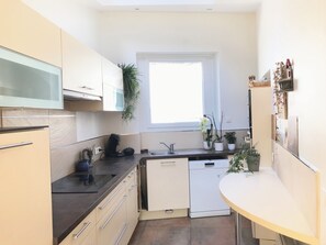 A modern kitchen with a dishwasher, a microwave, and a coffee maker. There is a window providing natural light and several potted plants. - Stunning villa, a 15-minute walk from the Route du Rhum (Saint-Malo)