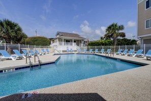 A swimming pool with blue chairs, a no diving sign, and a building in the background.