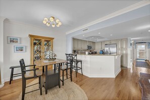 Een moderne keuken met witte kasten, een centraal eiland en een eethoek met een houten tafel en stoelen.