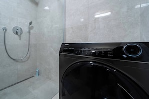 A modern bathroom with a black washing machine and a glass shower enclosure. - Urban Oasis Brno - I (Brno-město)