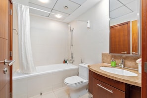 A modern bathroom with a bathtub, toilet, and sink. - bnbme - Stand Point A - 2BR (Dubai)