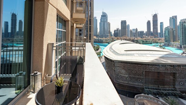 Un balcone con tavolo e sedie, affaccia su una città con grattacieli.