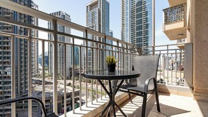 Un balcone con tavolo e sedie, vista su uno skyline urbano con grattacieli.