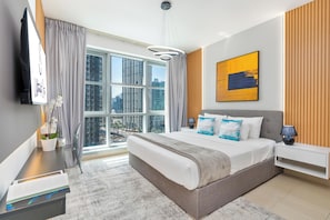A modern hotel room with a large bed, a city view, a flat-screen TV, and a painting on the wall. - bnbme - Stand Point A - 2BR (Dubai)