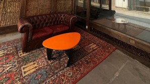 Una habitación con diseño tradicional, que incluye un sofá de cuero, una pequeña mesa redonda y una alfombra estampada.