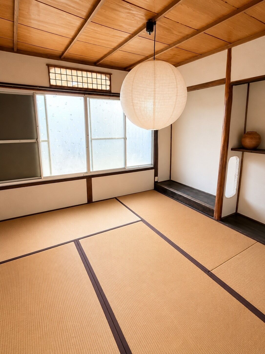 A traditional Japanese room with tatami flooring, a shoji screen, and a hanging paper lantern.