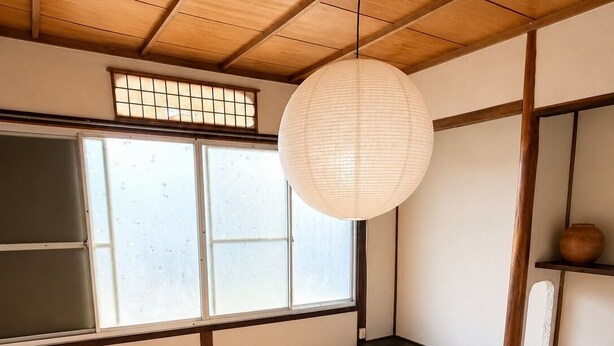 Una habitación japonesa tradicional con suelo de tatami, un panel de shoji y un farolillo de papel colgante.
